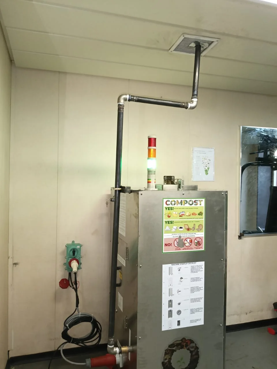 The Innovus composter installed on board the ship, with its exhaust pipe running to a ceiling vent